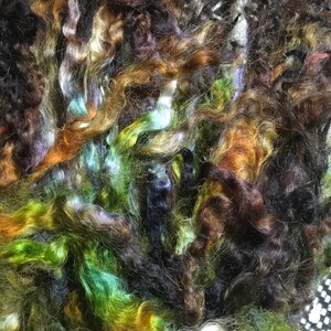 May include: A pile of colorful yarn in shades of brown, green, blue, and white. The yarn is soft and fluffy, and it would be perfect for knitting or crocheting.