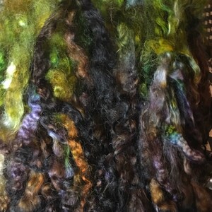 May include: A bundle of colorful yarn in shades of green, brown, black, and purple. The yarn is soft and fluffy, and it would be perfect for knitting or crocheting.