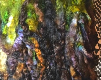 May include: A bundle of colorful yarn in shades of green, brown, black, and purple. The yarn is soft and fluffy, and it would be perfect for knitting or crocheting.