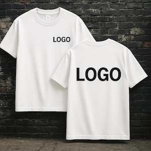 May include: Two white t-shirts, each displaying the word "LOGO" in black, one on the front and one on the back. The shirts are short-sleeved with a crew neck. The backdrop is a dark brick wall.