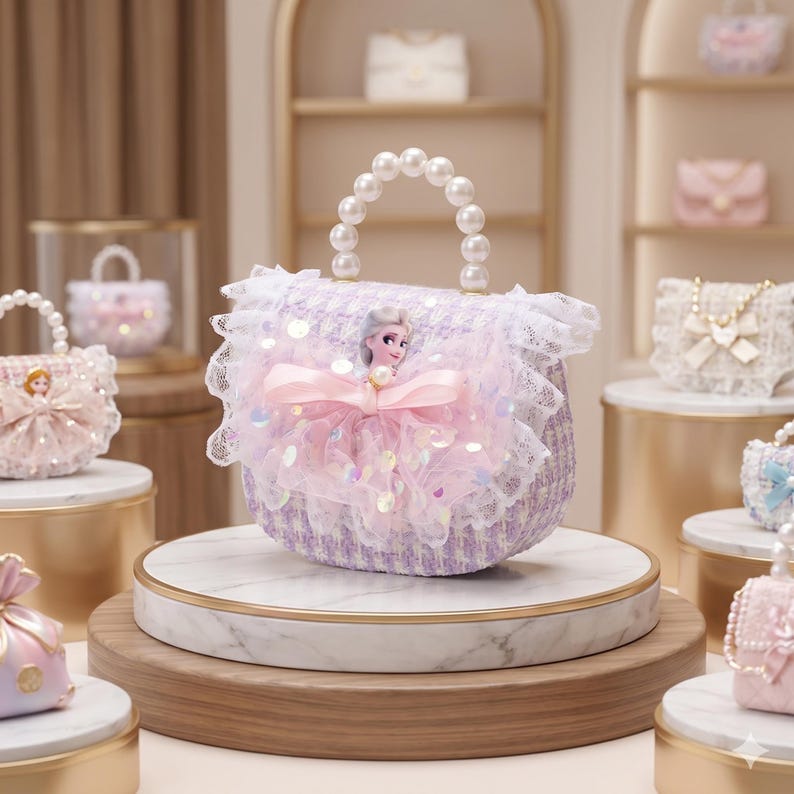 K&ouml;nnte beinhalten: Eine lavendelfarbene und wei&szlig;e Tweed-Handtasche mit einem Perlenhenkel, wei&szlig;er Spitzenborte und einer zentralen rosa T&uuml;llschleife, die mit einer kleinen Elsa-Figur aus dem Film Die Eisk&ouml;nigin auf der Vorderseite verziert ist.