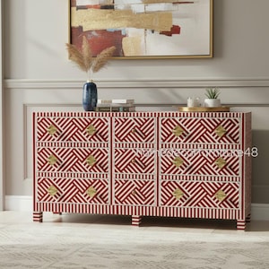 Op de afbeelding: Een rood en wit patroon dressoir met zes lades en goudkleurige hardware. Het geometrische ontwerp is opvallend en het dressoir is een stijlvolle opbergoplossing. Het dressoir is ongeveer 152 cm breed.