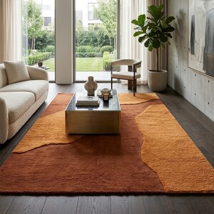 Terracotta and mustard abstract wool rug styled in a living room, adding warm earthy color and organic movement to the floor.