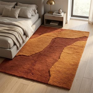 Warm terracotta and mustard hand-tufted wool rug styled in a bedroom, creating a cozy earthy accent with an organic abstract design.