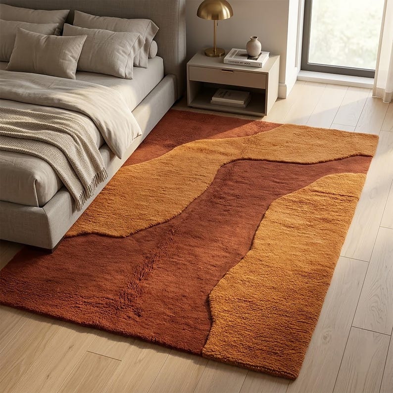 Warm terracotta and mustard hand-tufted wool rug styled in a bedroom, creating a cozy earthy accent with an organic abstract design.