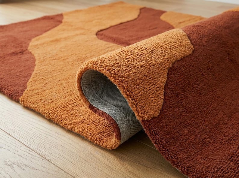 Folded-edge view of the hand-tufted wool rug showing its textured pile, layered surface, and terracotta brown and mustard ochre color blocks.