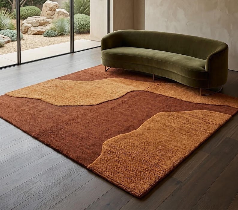 Terracotta and mustard abstract wool rug styled in a living room, adding warm earthy color and organic movement to the floor.