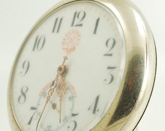 May include: Silver pocket watch with a white face and black numerals. The watch has a small seconds dial and ornate hands. The watch has a loop at the top for a chain. The watch face has the text "SCHAFFHAUSEN" and "MOSKOFF".