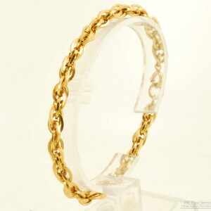 May include: A gold chain bracelet with a rope-like design. The bracelet is displayed on a clear stand.