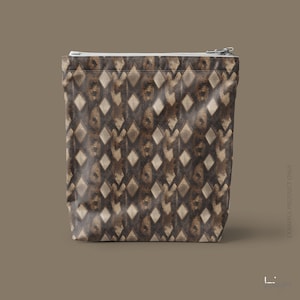 May include: A rectangular zippered pouch featuring a repeating diamond pattern in shades of dark brown, tan, and cream. The fabric has a textured appearance with a metallic silver zipper closure along the top edge of the bag.