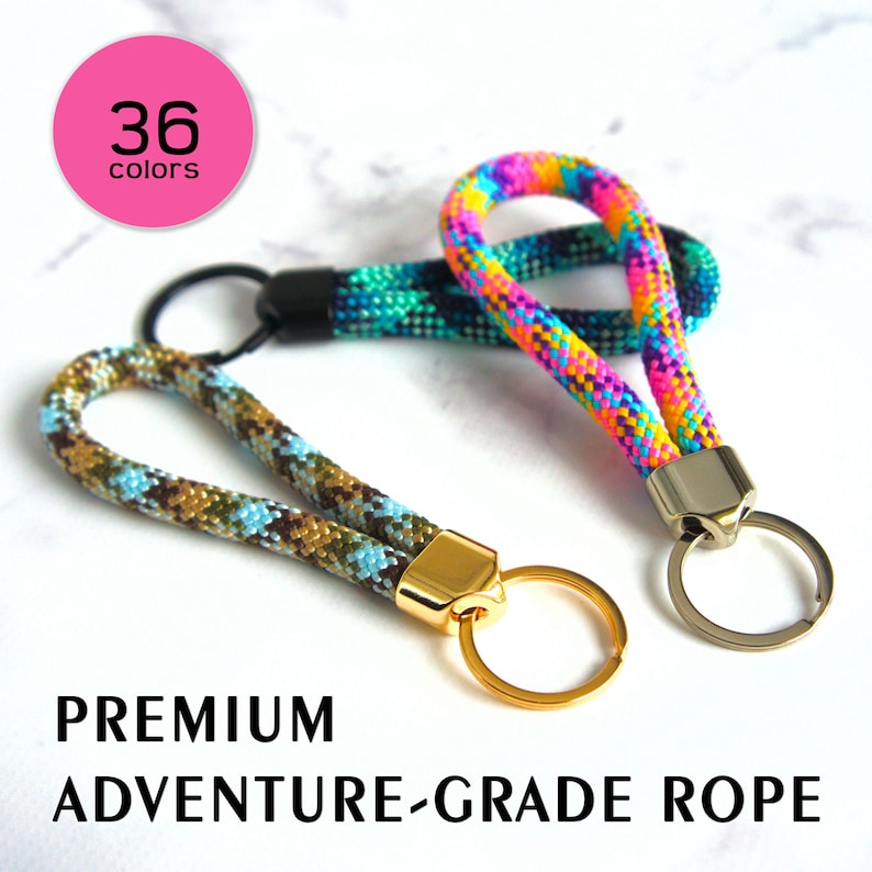 May include: Three keychains with colorful rope loops. One is rainbow-colored, another is teal and black, and the third is brown, blue, and tan. The keychains have gold and silver-colored metal hardware. Text reads "PREMIUM ADVENTURE-GRADE ROPE" and "36 colors."