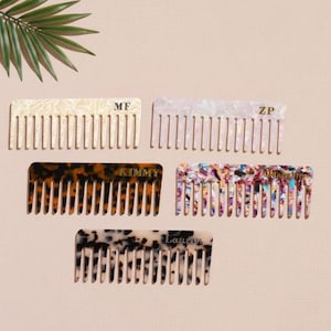 May include: Five decorative combs in various colours and patterns. One is cream-coloured with the initials "MF", another is pearlescent with "ZP", a third is tortoiseshell with "KIMMY", a fourth is multi-coloured, and the last is black and white with "Lauren".