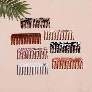 Puede incluir: Una colección de peines personalizados en varios colores y patrones. Los peines presentan nombres como "Alex", "Manon" y "Shannon" en letras doradas. Los peines están hechos de un material veteado y tienen un diseño de peine clásico.