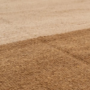 May include: Close-up of a textured rug with a diagonal color block design. The rug features two shades of brown, with a lighter tan color in the upper portion and a darker brown in the lower portion.