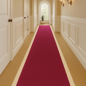 Peut inclure: Un long tapis de couloir rectangulaire bordeaux avec une bordure crème. Le tapis est placé dans un couloir aux murs clairs, avec des boiseries blanches et un sol en bois. Le couloir a deux portes à gauche et une fenêtre au bout.