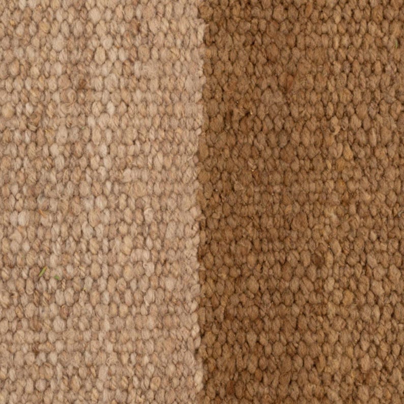 May include: Close-up of a textured rug with two vertical sections. One section is a light tan color, and the other is a medium brown. The rug has a woven appearance, with visible fibers and a nubby texture.