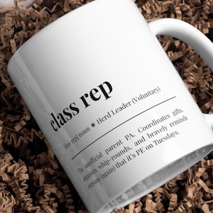 May include: White ceramic mug featuring the words "class rep" in a bold, black font. The mug includes a definition and description of the role, with the words "Herd Leader (Voluntary)" and other text in a smaller font.