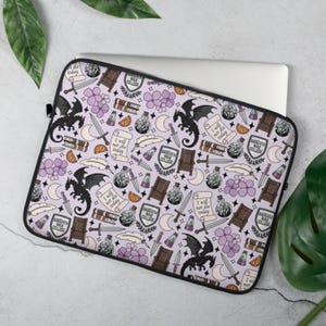 May include: A laptop sleeve with a repeating pattern of black dragons, swords, scrolls, chairs, and text on a light purple background. The text includes "I will not die today" and "Basgiath War College".