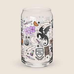May include: A clear glass can-shaped drinking glass decorated with fantasy-themed illustrations. The design includes a black dragon, daggers, scrolls, purple flowers, and the text "Basgiath War College".
