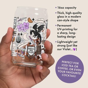 May include: A clear glass can-shaped drinking glass with a decorative design featuring a black dragon, daggers, flowers, and the text "Basgiath War College." The glass has a 16oz capacity.