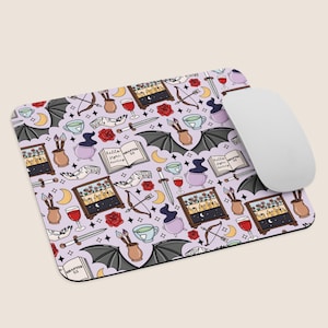 Könnte beinhalten: Ein lavendelfarbenes Mauspad mit einem sich wiederholenden Muster von Illustrationen zum Thema Hexerei und Fantasy. Das Design umfasst Monde, Fledermäuse, Zaubertränke, Rosen, Bögen, Schwerter, Teetassen und Bücher mit dem Text "Hello, here darling" und "Chapter 55". Eine weiße Computermaus befindet sich rechts.