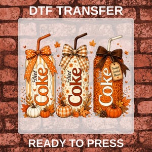 May include: A DTF transfer featuring three soda cans with autumn themes. Each can has a straw, a bow, and fall foliage with pumpkins. The cans are labeled Diet Coke. The first has orange stripes, the second has floral patterns, and the third has a leopard print with a tag reading Thankful Grateful Blessed.