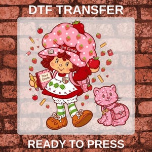 May include: A DTF transfer design featuring a cartoon character with brown hair wearing a pink strawberry-patterned hat and dress, holding a red apple and a book labeled 3rd Grade. A pink polka-dot cat sits nearby, surrounded by small strawberries and school supplies.