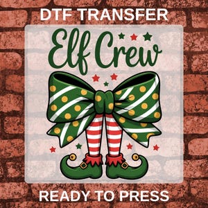 May include: A DTF transfer sheet featuring the text "DTF TRANSFER" at the top and "READY TO PRESS" at the bottom. The central graphic shows a large green polka-dot bow above two elf legs in red and white striped stockings and green curled shoes.