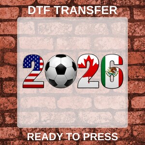 May include: A DTF transfer graphic featuring the text DTF TRANSFER at the top and READY TO PRESS at the bottom. The number 2026 is displayed with the 2 filled with the US flag, a soccer ball as the 0, a maple leaf for the 6, and the Mexican flag.