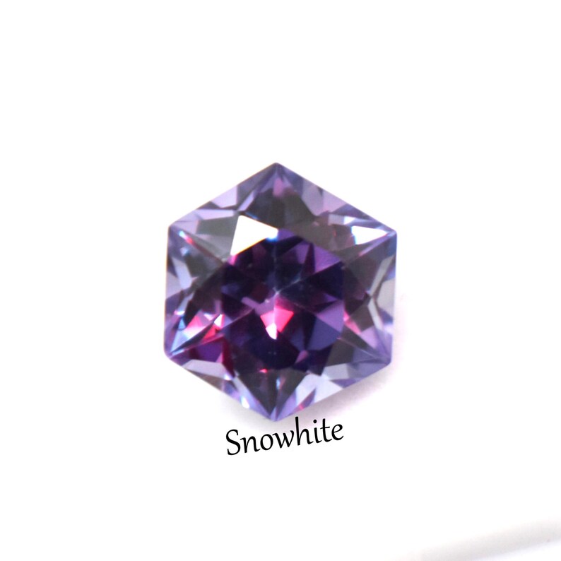 May include: A faceted hexagonal gemstone displaying a vibrant gradient of deep purple and magenta hues with sharp geometric edges. The word Snowwhite is printed in a simple black serif font directly beneath the stone on a plain white background.