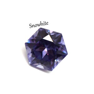 May include: A faceted, hexagonal-shaped gemstone in a deep purple hue with light-reflecting surfaces. The word Snowwhite is printed in black text above the stone. The gem displays sharp geometric edges and a brilliant, polished finish throughout.