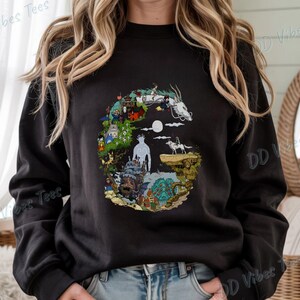 Puede incluir: Sudadera negra con un dise&ntilde;o gr&aacute;fico colorido que representa escenas y personajes de una pel&iacute;cula de animaci&oacute;n. El dise&ntilde;o incluye un drag&oacute;n blanco, una luna llena y varias figuras. El texto "DD Vibes Tees" est&aacute; impreso en la manga.