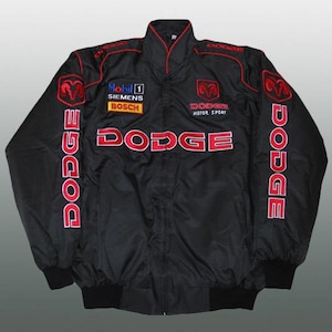 Puede incluir: Chaqueta de carreras Dodge negra con detalles rojos. Presenta el logotipo de Dodge en el pecho, las mangas y la espalda. Incluye logotipos de patrocinadores como Mobil 1, Siemens y Bosch. Tiene cuello alzado y cremallera completa.