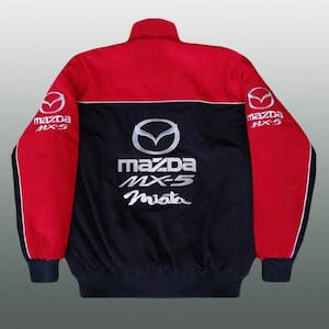 Puede incluir: Chaqueta Mazda MX-5 roja, negra y blanca. La chaqueta tiene cuello alto, una sección central negra con el logo de Mazda y "MX-5 Miata" en blanco, y mangas rojas con el logo de Mazda. La chaqueta tiene un diseño deportivo.