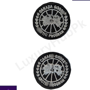 Puede incluir: Dos parches bordados circulares en blanco y negro. Cada parche presenta las palabras "CANADA GOOSE" y "ARCTIC PROGRAM" alrededor de un diseño central. Probablemente son parches para ropa.