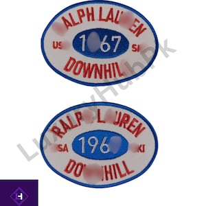 Peut inclure: Deux écussons ovales avec texte brodé. Le patch supérieur indique "ALPH LAUREN 167 DOWNHILL". Le patch inférieur indique "RALPH LAUREN 196 DO HILL". Les deux écussons ont un fond blanc avec des accents rouges et bleus.