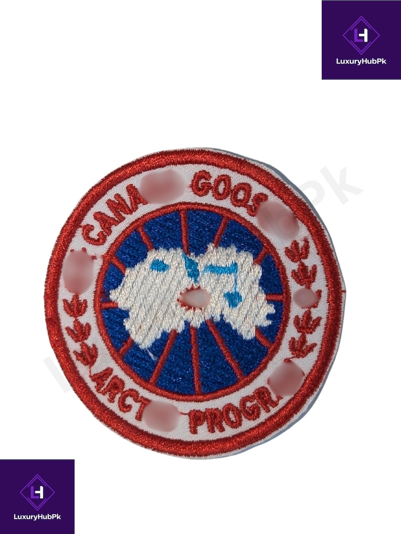 May include: Embroidered patch featuring a circular design with the text "CANA GOOS ARCT PROGR". The patch has a red border, a blue and white center with a map design, and white text. The patch is likely for clothing or accessories.