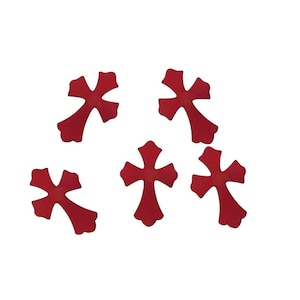 May include: Five red cross-shaped embellishments with rounded edges are scattered against a white background. The crosses are evenly spaced and appear to be made of a solid material.