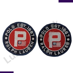May include: Two circular patches with a red centre and a white "P" logo, surrounded by navy blue text and a white border. The text reads "POLO RALPH LAUREN" and "EST. 1967". Each patch features a small American flag.
