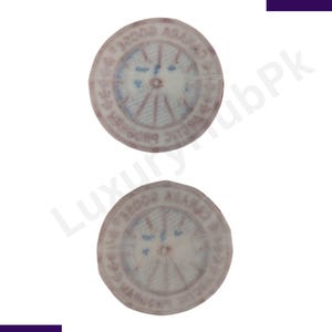 May include: Two circular, vintage-style stamps with faded red and blue details. The stamps feature text around the edges and a central design with radial lines. The stamps are set against a white background.
