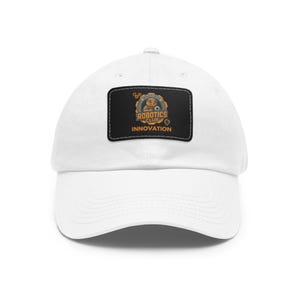 May include: White baseball cap with a curved brim. The cap features a rectangular patch with the words "Robotics Club Innovation" and a graphic of a robot. The patch is black with orange and white details.