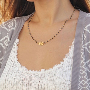May include: A gold hamsa hand charm necklace with black beads.