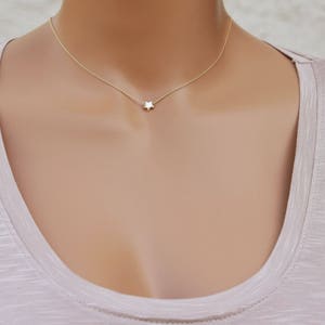 Puede incluir: Un delicado collar de cadena dorada con un peque&ntilde;o colgante de estrella blanca.