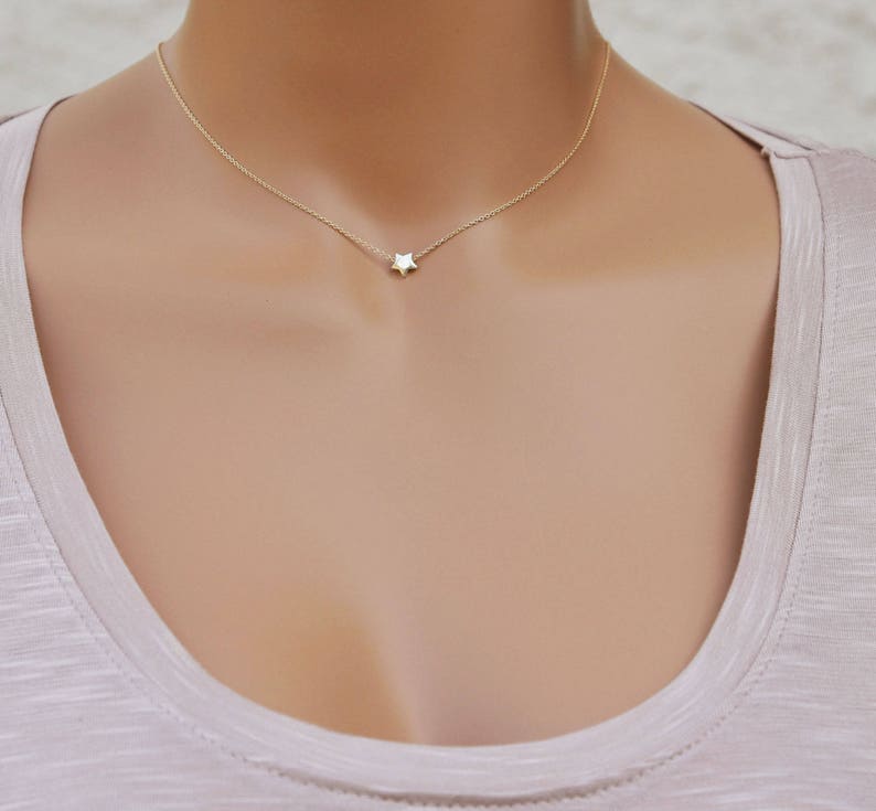 Puede incluir: Un delicado collar de cadena dorada con un peque&ntilde;o colgante de estrella blanca.