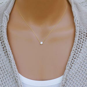 Puede incluir: Un delicado collar de cadena dorada con un peque&ntilde;o colgante de estrella blanca.