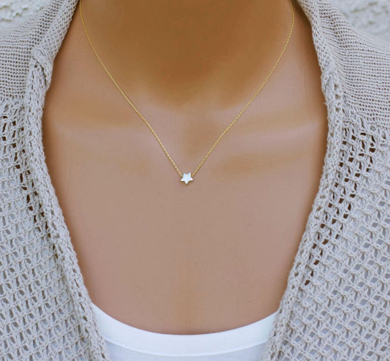 Puede incluir: Un delicado collar de cadena dorada con un peque&ntilde;o colgante de estrella blanca.