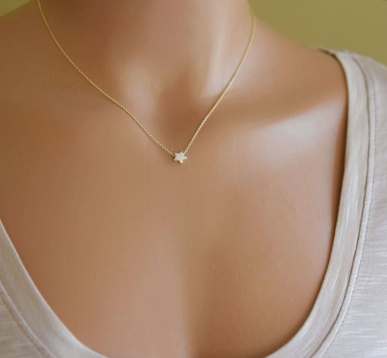 Puede incluir: Un delicado collar de cadena de oro con un peque&ntilde;o colgante en forma de estrella.