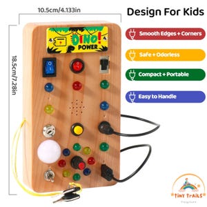 Op de afbeelding: Houten sensorbord voor kinderen, 10,5 cm breed en 18,5 cm hoog. Voorzien van kleurrijke knoppen, schakelaars en een "DINO! POWER" afbeelding. Inclusief sleutel en stekker, ontworpen voor eenvoudige bediening en compacte draagbaarheid.