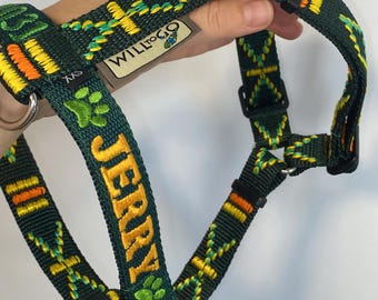 May include: Green dog harness with yellow and orange accents. The harness has the name "JERRY" embroidered in yellow, along with a green paw print. The brand name "WILLtoGO" is visible on a tag.