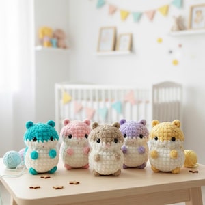 Könnte beinhalten: Fünf handgefertigte Häkeltier-Hamster in Türkis, Rosa, Braun, Lila und Gelb. Jeder Hamster hat einen weißen Bauch und sitzt auf einem hellen Holztisch. Die Spielzeuge befinden sich in einem Kinderzimmer.